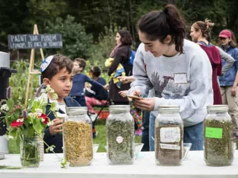 a person and a child at a table with jars of food