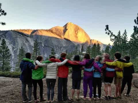 a group of people posing for a photo in front of a mountain