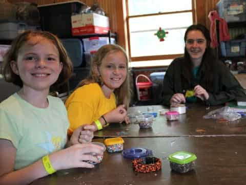 a group of children sitting at a table with small cups of food