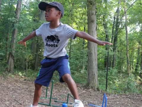 a boy jumping over a trampoline in the woods
