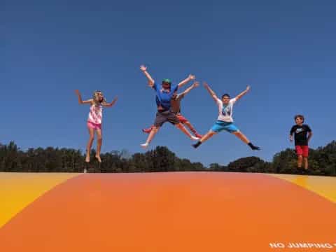 a group of people jumping on an orange slide