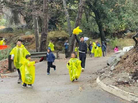 a group of people in clothing walking on a path in the woods