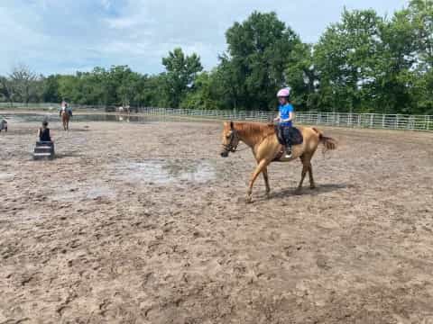 a girl riding a horse in a muddy arena