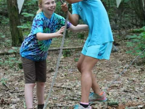 a couple of girls on a swing in the woods