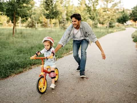 a man pushing a child on a tricycle