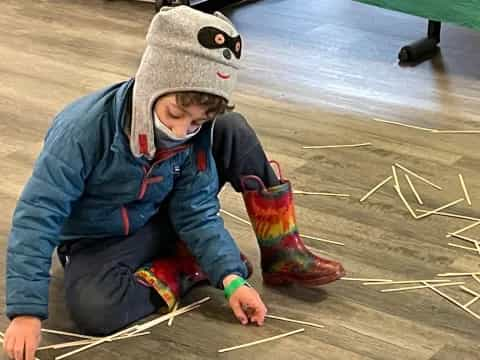 a boy wearing a hat and kneeling on the ground