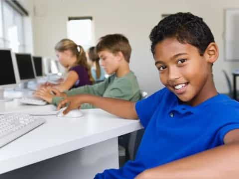 a group of people sitting at a table with computers