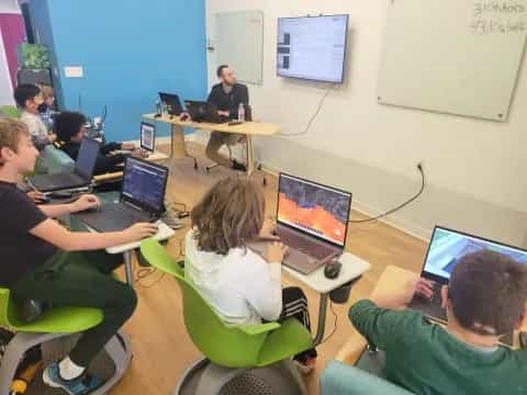 a group of people sitting at a table with laptops