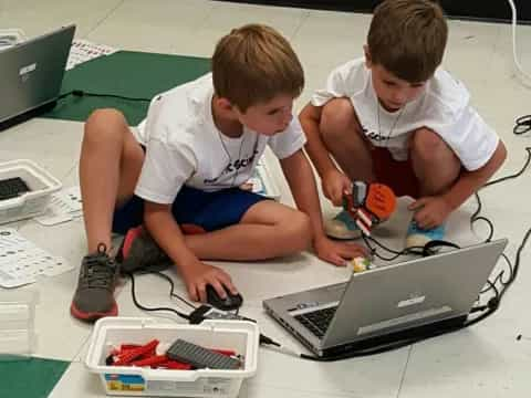 boys sitting on the floor using laptops