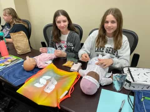 a group of girls sitting at a table with a child's toy