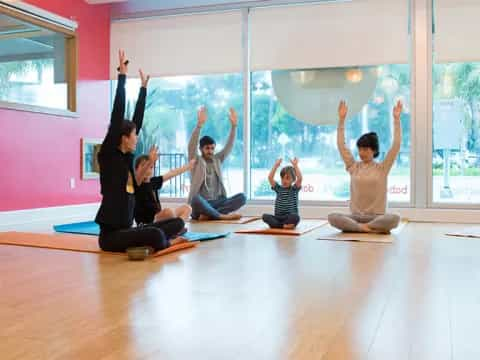 a group of people sitting on the floor with their arms raised