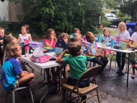 a group of children sitting around a table outside