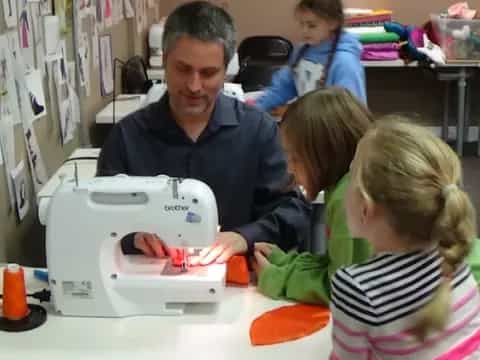 a person and children looking at a sewing machine