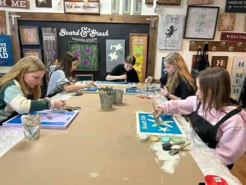 a group of people sitting at a table painting
