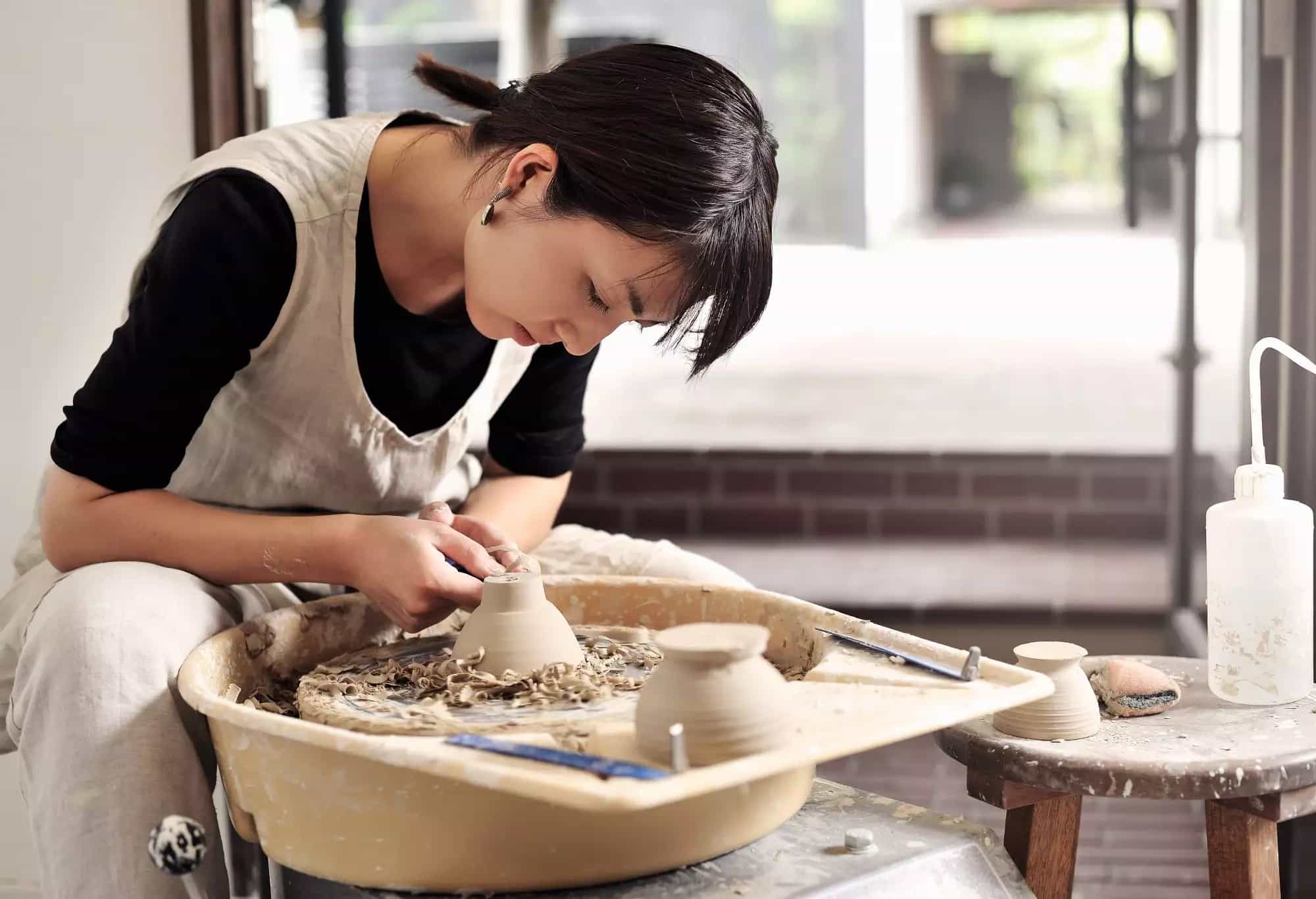 a woman making a clay pot