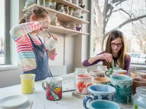 a couple of girls sitting at a table with cups and saucers