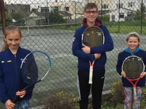 a group of kids holding tennis rackets