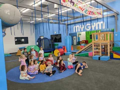 a group of children posing for a photo in a room with a stage