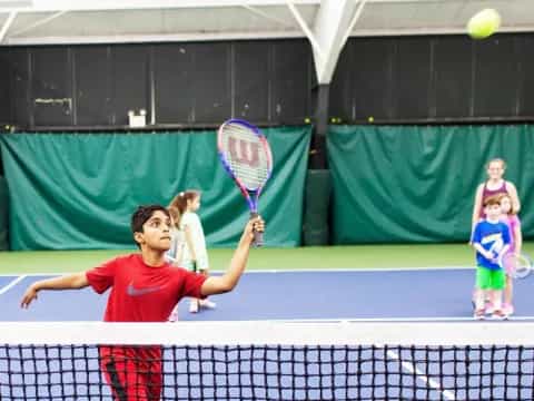 a kid hitting a ball with a tennis racket