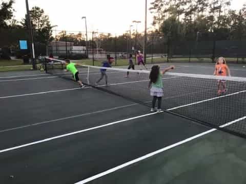 a group of kids playing tennis