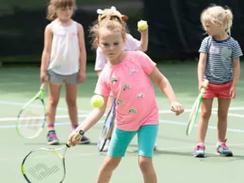 a group of kids playing tennis