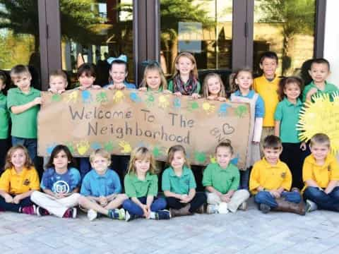 a group of children posing for a photo with a sign