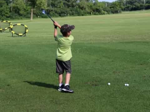 a boy swinging a golf club