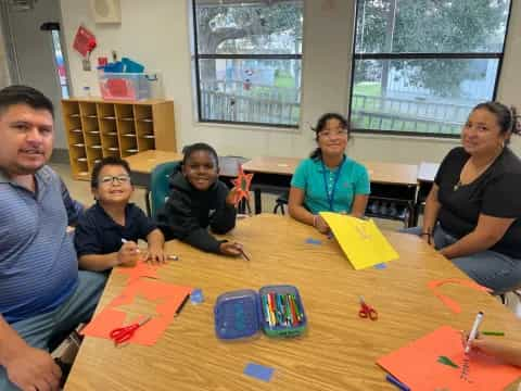 a group of people sitting around a table with colorful paper on it