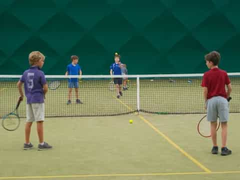 a group of kids playing tennis