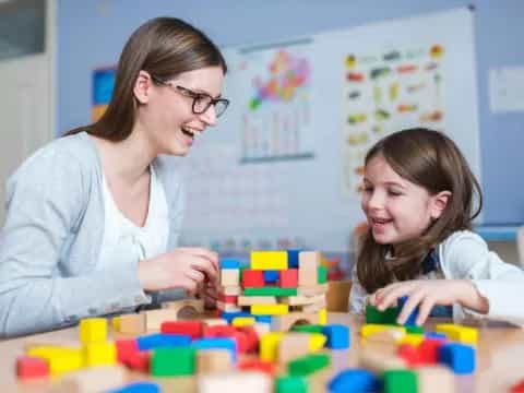 a woman and a girl playing with blocks