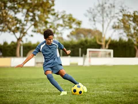 a boy kicking a football ball