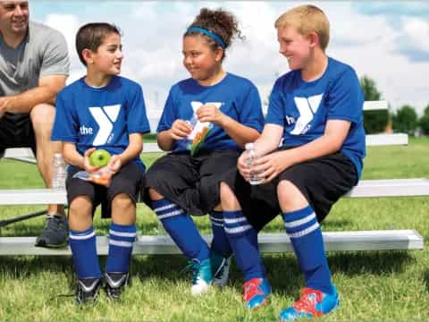 a group of boys sitting on a bench with balls