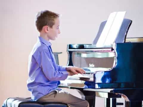 a boy sitting at a piano