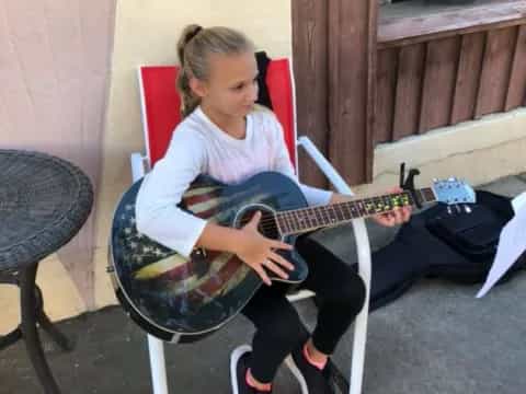 a girl sitting in a chair playing a guitar