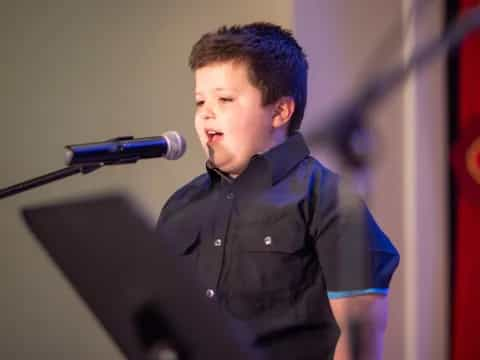 a boy standing in front of a microphone