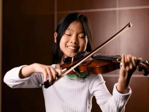 a young girl playing a violin