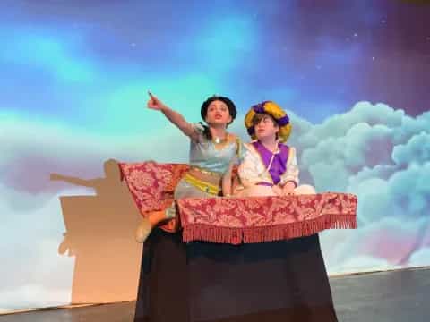 two women sitting on a large rock