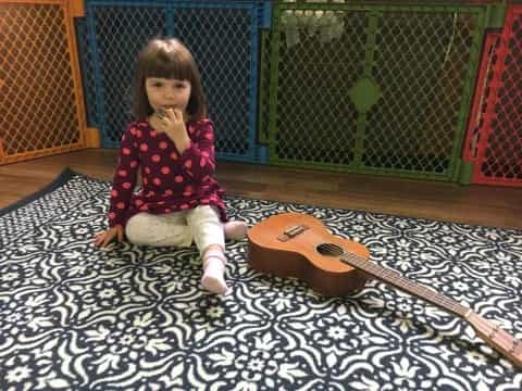 a girl sitting on the floor next to a guitar