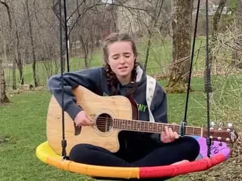 a girl sitting on a swing playing a guitar