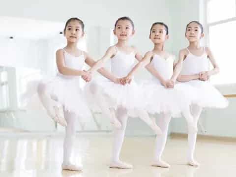 a group of girls in white ballet outfits