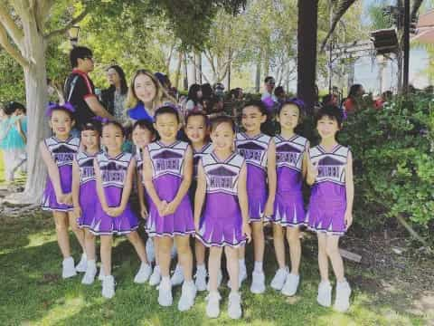 a group of girls in purple and white uniforms standing in a line