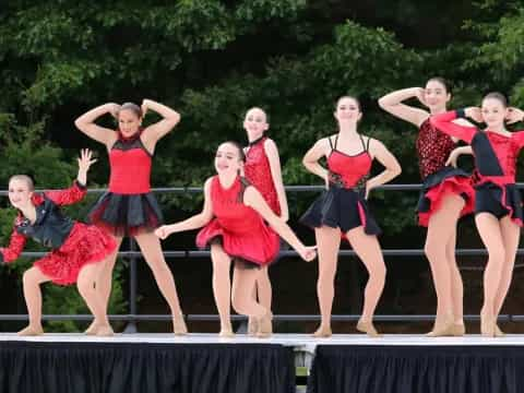 a group of girls in red and black dresses on a stage