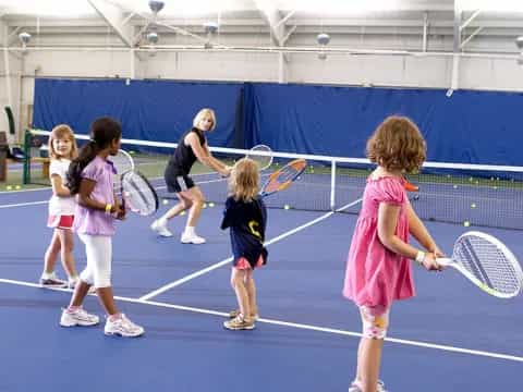 a group of kids playing tennis