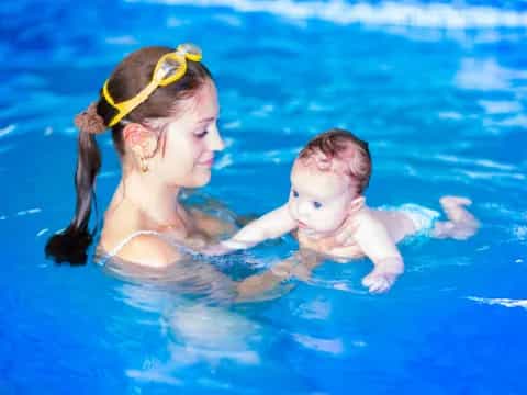 a woman holding a baby in a pool