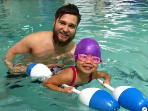 a woman and a girl in a pool with balls