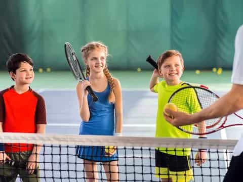 a group of kids playing tennis