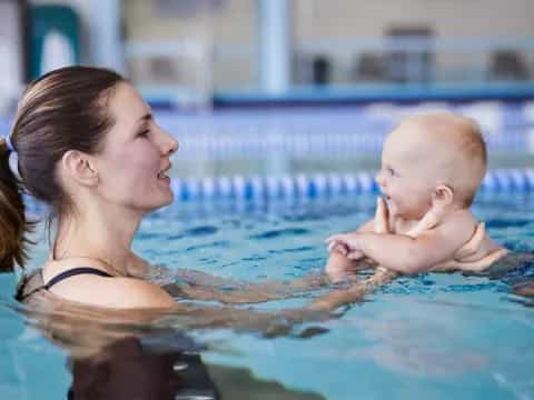 a woman holding a baby in a pool