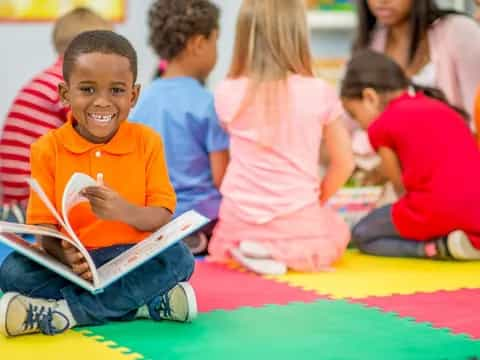 a boy sitting on the floor reading a book