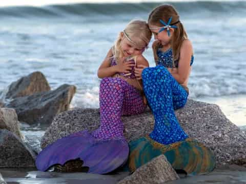 two girls sitting on rocks by the water