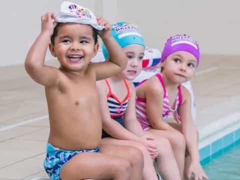 a group of children in swimsuits by a pool